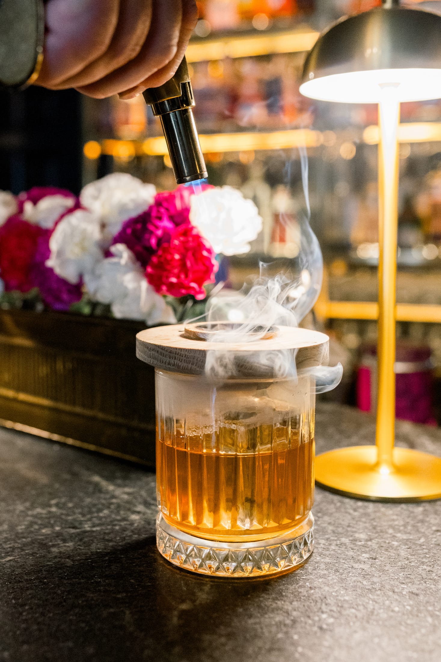 A bartender using a Sentinel smoker with a torch